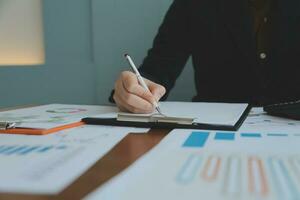 Group of confident business people point to graphs and charts to analyze market data, balance sheet, account, net profit to plan new sales strategies to increase production capacity. photo