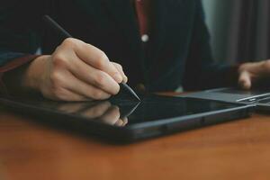 Asian Businesswoman Using laptop computer and working at office with calculator document on desk, doing planning analyzing the financial report, business plan investment, finance analysis concept. photo