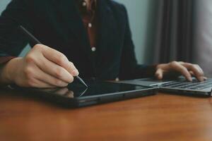 Asian Businesswoman Using laptop computer and working at office with calculator document on desk, doing planning analyzing the financial report, business plan investment, finance analysis concept. photo