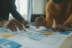 Close up ux developer and ui designer brainstorming about mobile app interface wireframe design on table with customer breif and color code at modern office.Creative digital development agency photo