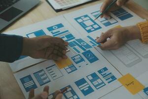 Close up ux developer and ui designer brainstorming about mobile app interface wireframe design on table with customer breif and color code at modern office.Creative digital development agency photo