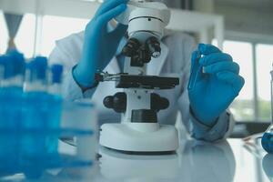 biochemical research scientist team working with microscope for coronavirus vaccine development in pharmaceutical research labolatory, selective focus photo