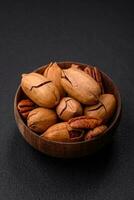 Pecan nuts in shell and peeled in a wooden round bowl photo