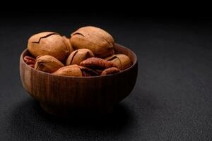 Pecan nuts in shell and peeled in a wooden round bowl photo