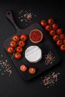 delicioso Fresco queso Brie queso en el formar de un mini cabeza con Cereza Tomates foto