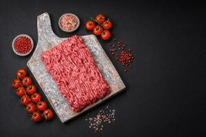 Raw ground beef or pork on a wooden cutting board with spices and salt photo
