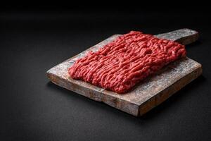 Raw ground beef or pork on a wooden cutting board with spices and salt photo