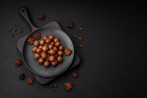 Delicious roasted macadamia nuts in shell on a dark textured background photo