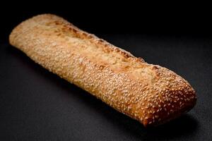 Crispy wheat flour baguette with sesame seeds on a wooden cutting board photo