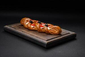 Delicious fresh crispy pastry in the form of a pigtail with strawberries and blueberries photo