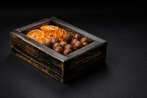 Delicious roasted macadamia nuts in shell on a dark textured background photo