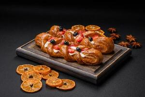 Delicious fresh crispy pastry in the form of a pigtail with strawberries and blueberries photo