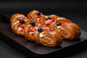 Delicious fresh crispy pastry in the form of a pigtail with strawberries and blueberries photo