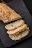 Crispy wheat flour baguette with sesame seeds on a wooden cutting board photo