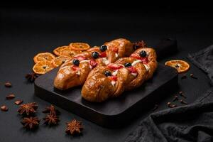 Delicious fresh crispy pastry in the form of a pigtail with strawberries and blueberries photo