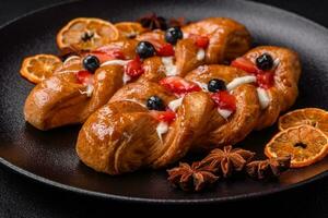 Delicious fresh crispy pastry in the form of a pigtail with strawberries and blueberries photo