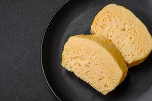 Delicious porous yellow cheese cut in large pieces on a ceramic plate photo