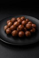 Delicious roasted macadamia nuts in shell on a dark textured background photo