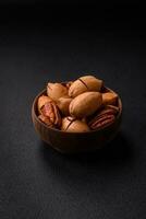 Pecan nuts in shell and peeled in a wooden round bowl photo