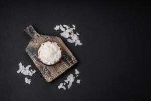 White dry coconut flakes in a wooden bowl prepared for making desserts photo