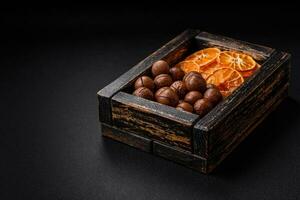 Delicious roasted macadamia nuts in shell on a dark textured background photo