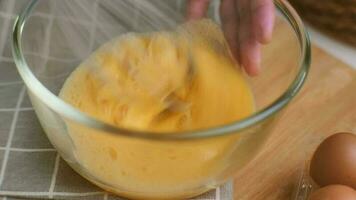 giovane donna cucinando nel luminosa cucina, mani sbattere uova nel un' ciotola posto su asciugamano e di legno tavolo. preparazione ingredienti per salutare cucinando. fatti in casa cibo video