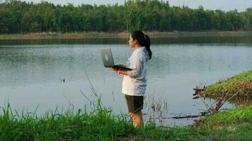 fêmea ecologista usando computador portátil computador para registro natural água contaminação Verificações. biólogo analisando água teste resultados usando tecnologia inscrição em computador portátil. água e ecologia conceito video