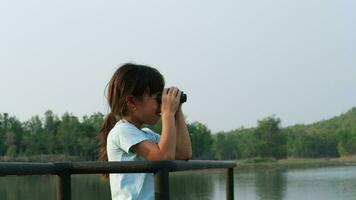 Little girl looking through binoculars at birds on the reservoir. Explore and adventure concept. Birdwatching video