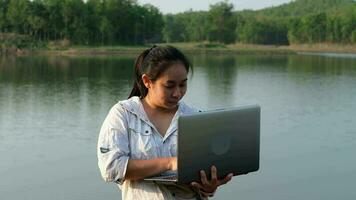 femmina ambientalista utilizzando il computer portatile computer per disco naturale acqua contaminazione controlli. biologo analizzando acqua test risultati utilizzando tecnologia applicazione su il computer portatile. acqua e ecologia concetto video