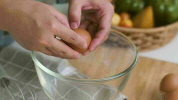 Young woman cooking in a bright kitchen, hand made cracked fresh egg yolks dripping into the bowl. Preparing ingredients for healthy cooking. Homemade food video