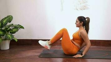 vídeo de un mujer en naranja gimnasio traje ejecutando plano estómago ejercicio a hogar video