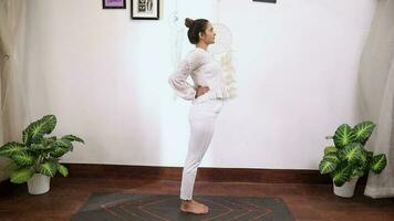 video van een vrouw het uitvoeren van half wiel houding yoga in voorkant van wit achtergrond