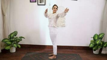 Video of a woman performing Standing Spinal Twist exercise in front of white background