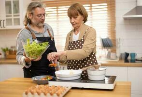 Couples in their golden years cook together. Deep talk can bring back vivid memories and romantic times. There is still a sense of fun, mutual understanding, commitment, support, and reliability. photo