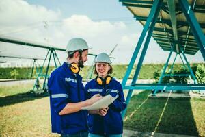 Solar engineers visually examine panel arrays on farm sites using blueprints and drawings to ensure that the alignment, surface, sunlight access, and structural stability meet standard requirements. photo