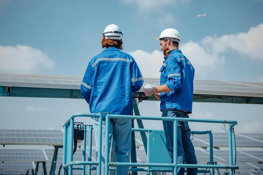 Solar engineers visually examine panel arrays on farm sites using blueprints and drawings to ensure that the alignment, surface, sunlight access, and structural stability meet standard requirements. photo