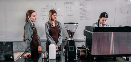 Young adult coffee makers work with skilled baristas to create menus. Using a coffee machine to make hot and cold coffee. Experiment with grinding and blending, including adding milk foam on top. photo