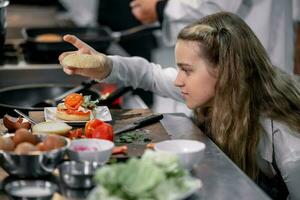 adolescentes aprender desde experto cocineros a culinario colegio a preparar ingredientes y crear un variedad de sabroso comidas. un práctico actividad conectado su Sentidos de gusto y oler es haciendo hamburguesas foto