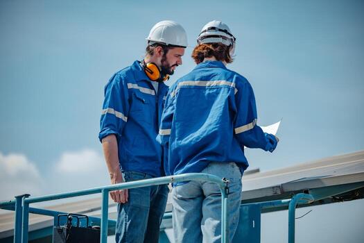 Solar engineers visually examine panel arrays on farm sites using blueprints and drawings to ensure that the alignment, surface, sunlight access, and structural stability meet standard requirements. photo