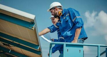 Solar engineers visually examine panel arrays on farm sites using blueprints and drawings to ensure that the alignment, surface, sunlight access, and structural stability meet standard requirements. photo