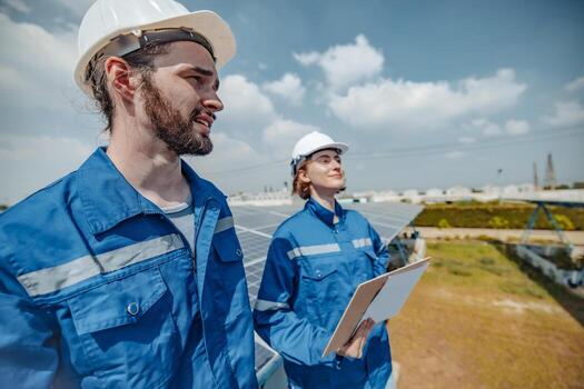 Solar engineers visually examine panel arrays on farm sites using blueprints and drawings to ensure that the alignment, surface, sunlight access, and structural stability meet standard requirements. photo