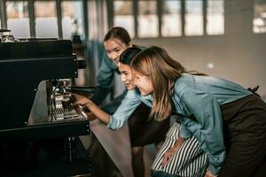 Young adult coffee makers work with skilled baristas to create menus. Using a coffee machine to make hot and cold coffee. Experiment with grinding and blending, including adding milk foam on top. photo