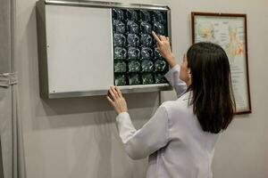 Physician and radiologist analyze medical images, including MRI film, to identify patient condition in order to develop treatment plans and future medical procedures, refer patients to specialists. photo