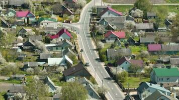 flying over a asphalt road in a village with sheds and garden plots video