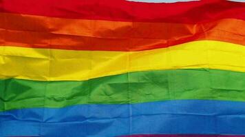 arco iris lgbt bandera revolotea encima el polo en el antecedentes de el azul cielo. concepto de libertad y género diversidad video