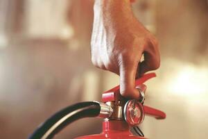 hand presses the trigger fire extinguisher available in fire emergencies conflagration damage background. Safety photo