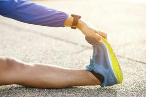 joven hombre corredor extensión para calentamiento arriba antes de corriendo o trabajando fuera en el la carretera. pista y campo atleta ejercicio. aptitud y deporte sano estilo de vida concepto. Copiar espacio bandera. foto