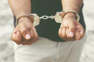 Prisoner male criminal standing in handcuffs with hands behind back. banner copy space. photo