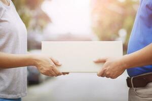 parcel delivery man wear protective gloves blue and mask, protect Hygiene germ and bacteria of a package through a service send to home. hand holding consign and submission customer accepting a of box photo