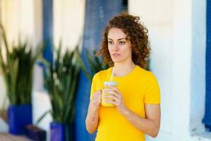 Pensive woman with juice in glass jar looking away photo